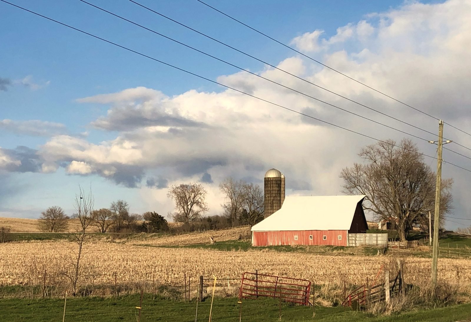 Red barn, silo and fence line in a harvested field
