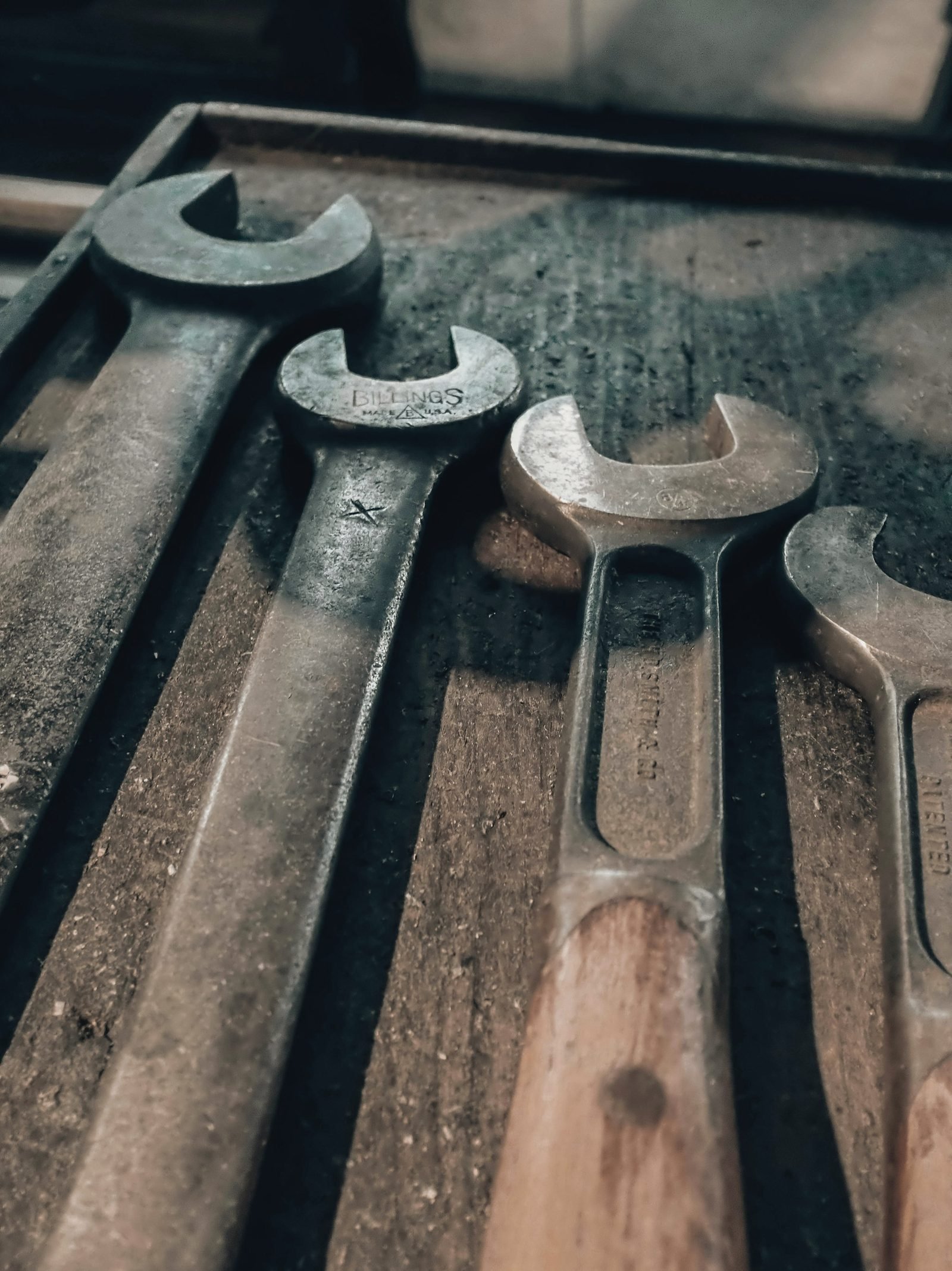 Worn open-end wrenches lying in a dusty tray